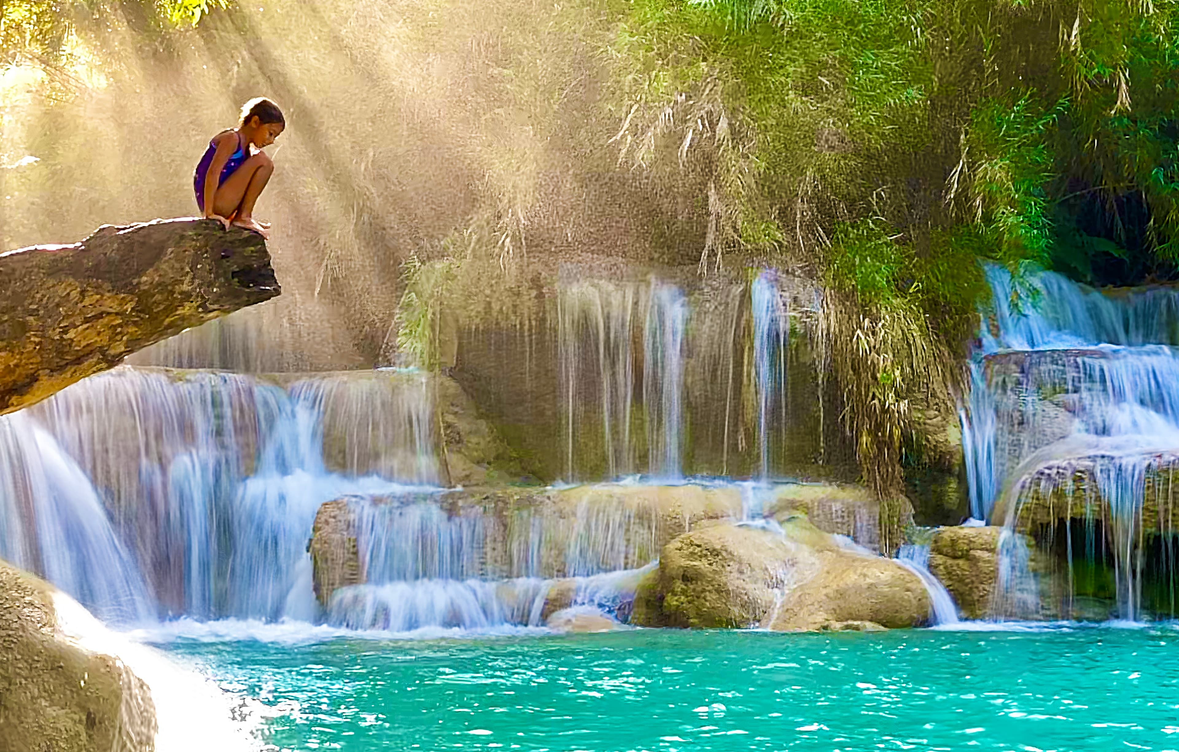 Mila on a tree branch above the turquoise pools at Kuang Si Falls, Laos